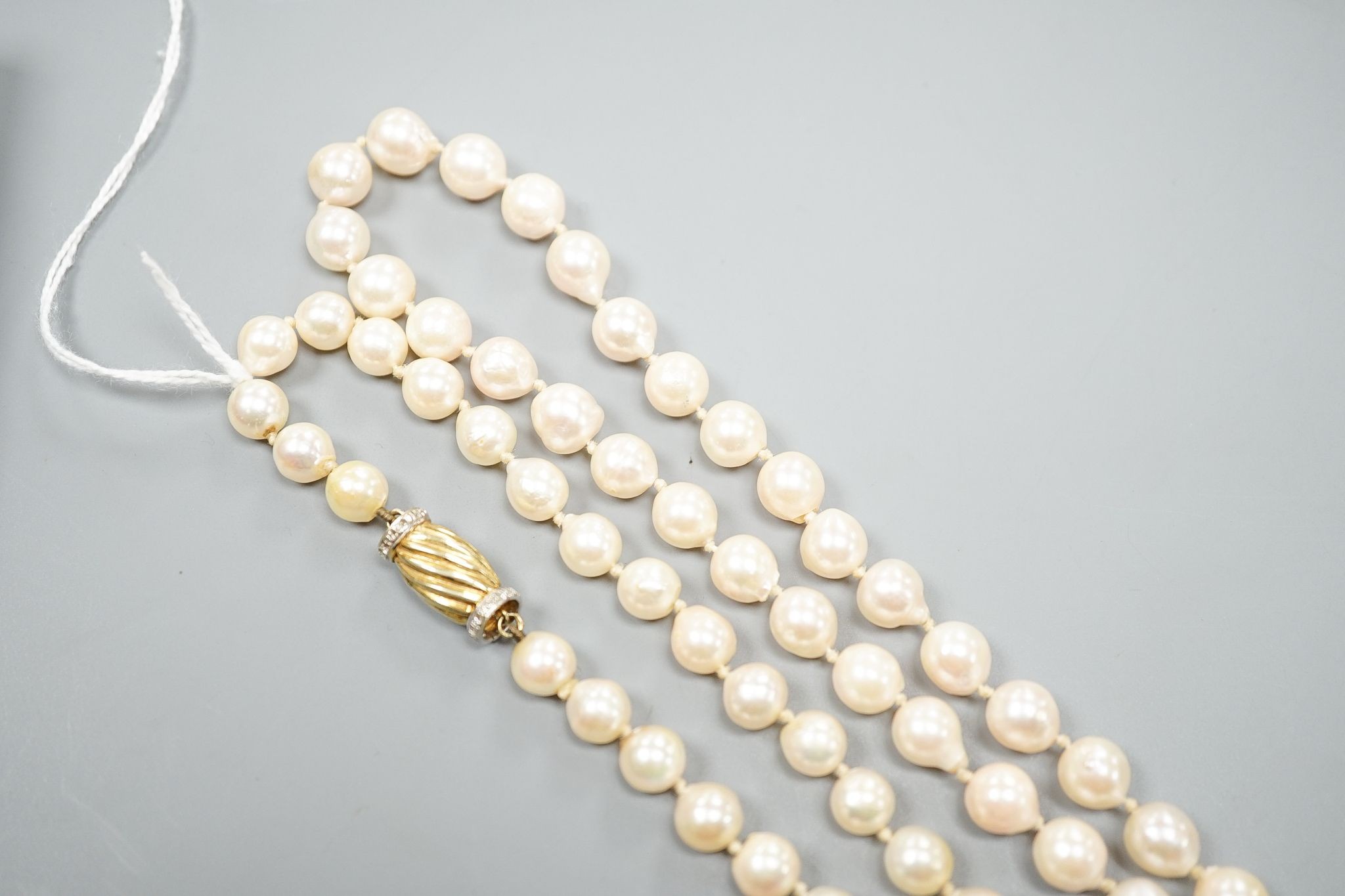 A modern long single strand cultured pearl necklace, with fluted 14k and diamond chip set clasp, 116cm.